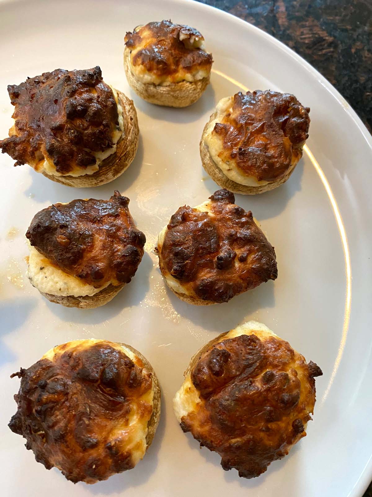 Cooked stuffed mushrooms on a white plate.