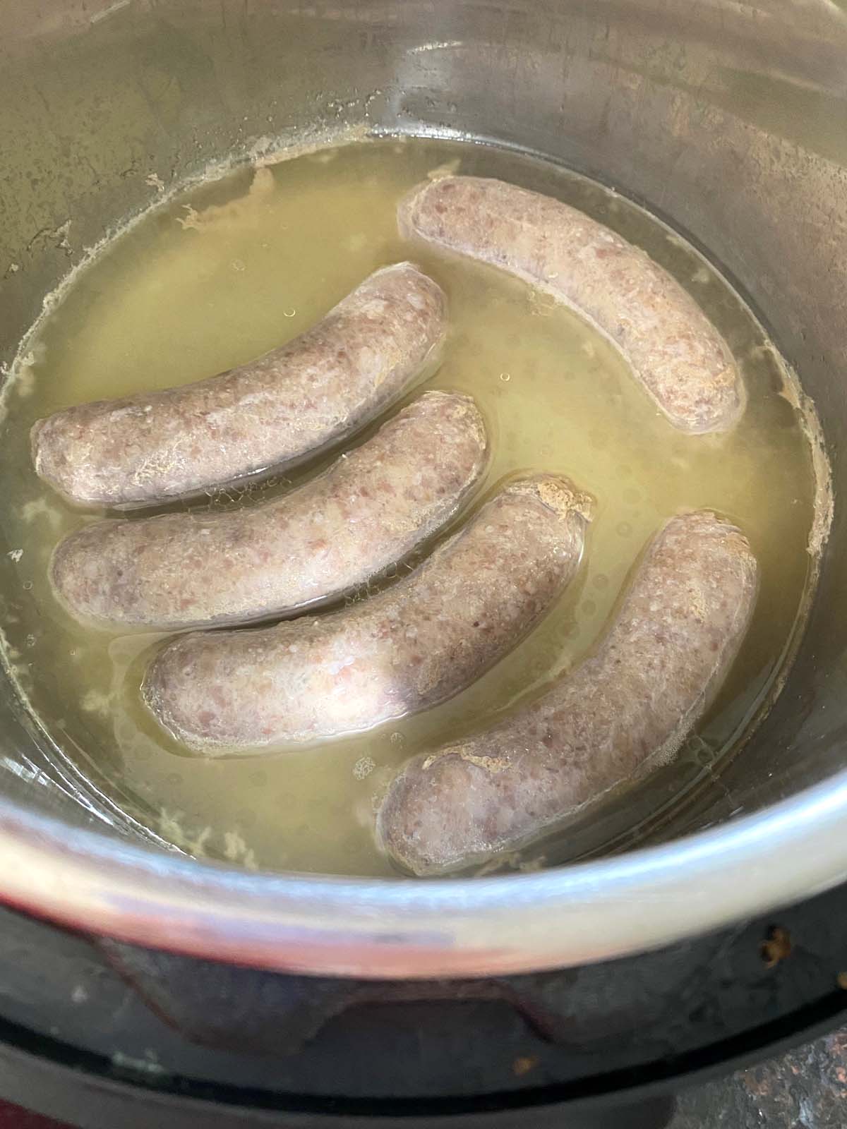 Bratwurst in pot with liquid after cooking.