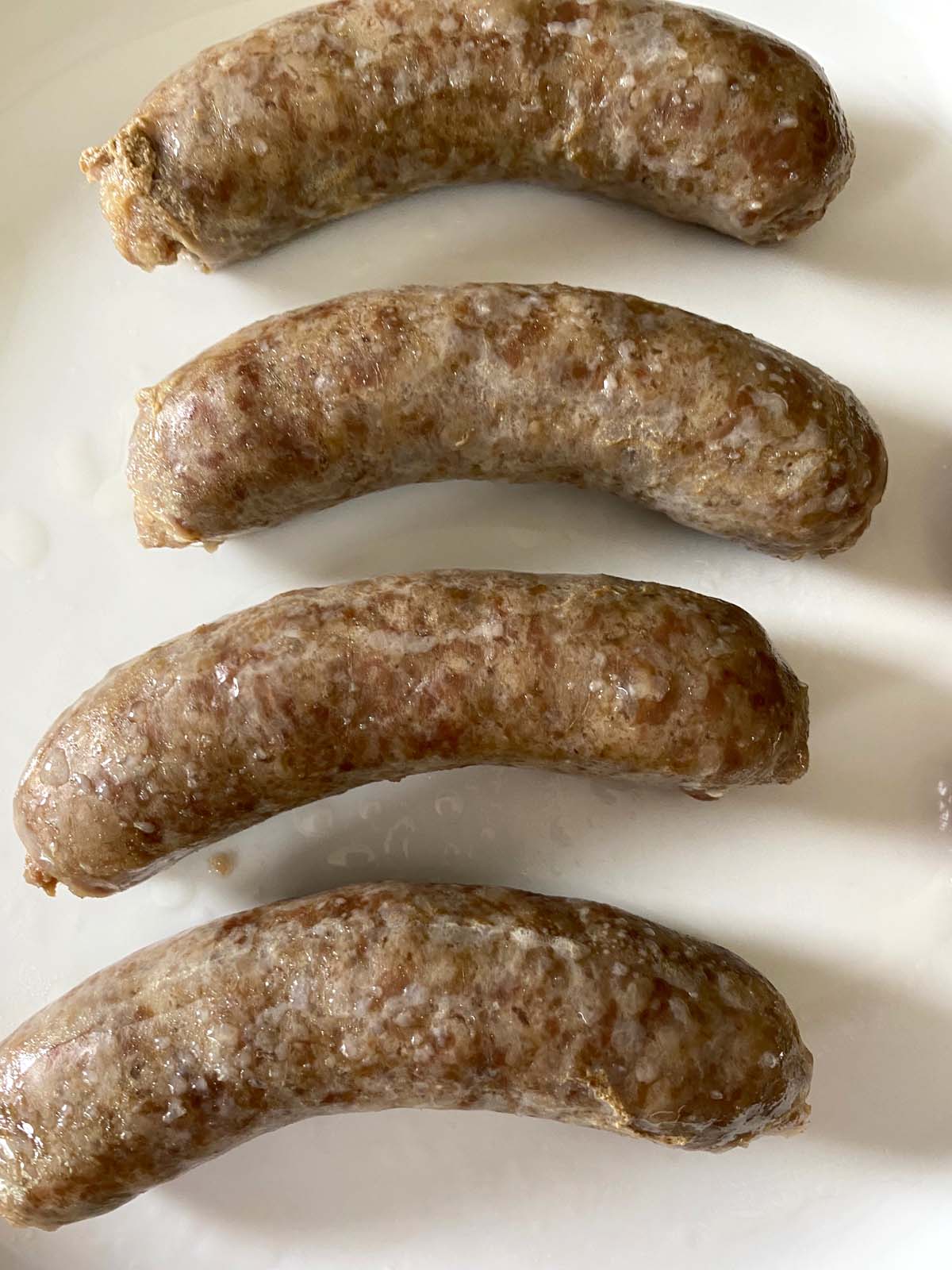 4 cooked brats on a plate.