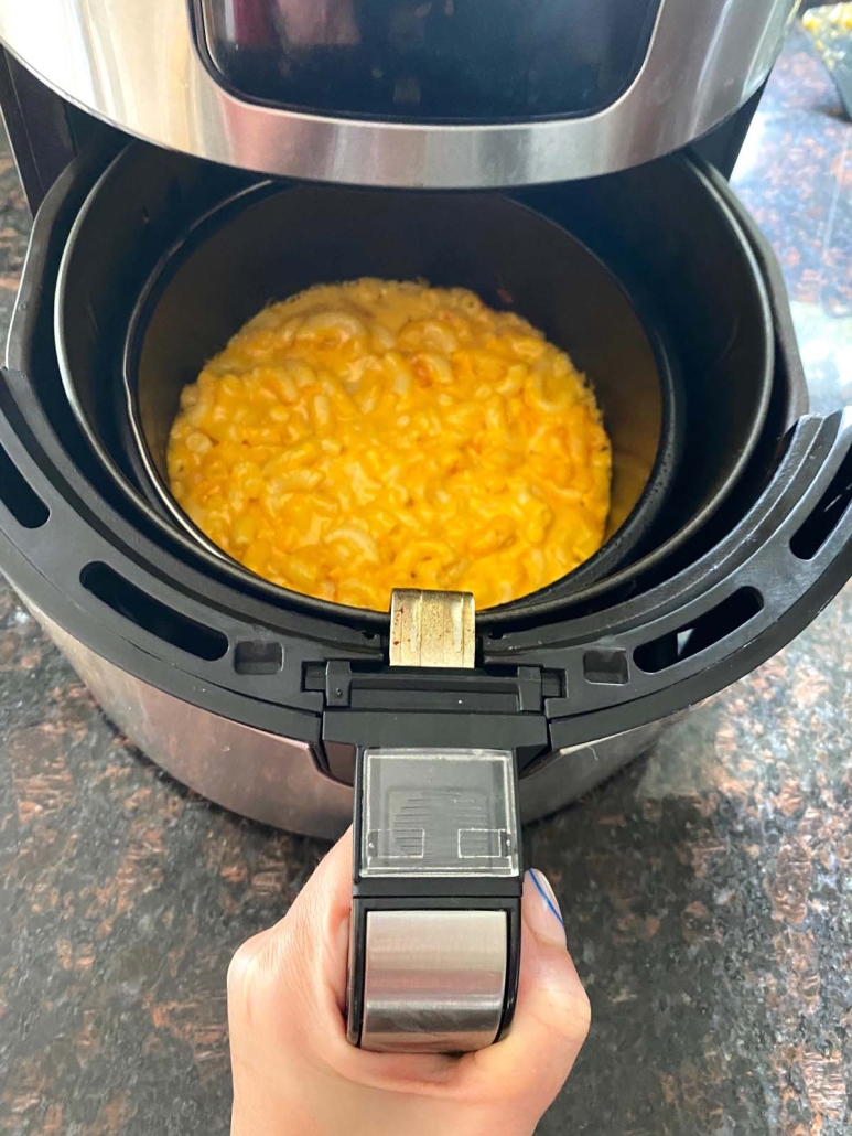 air fryer opened to show pan of frozen mac and cheese dinner