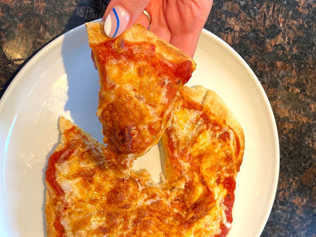 hand holding slice of cooked pizza