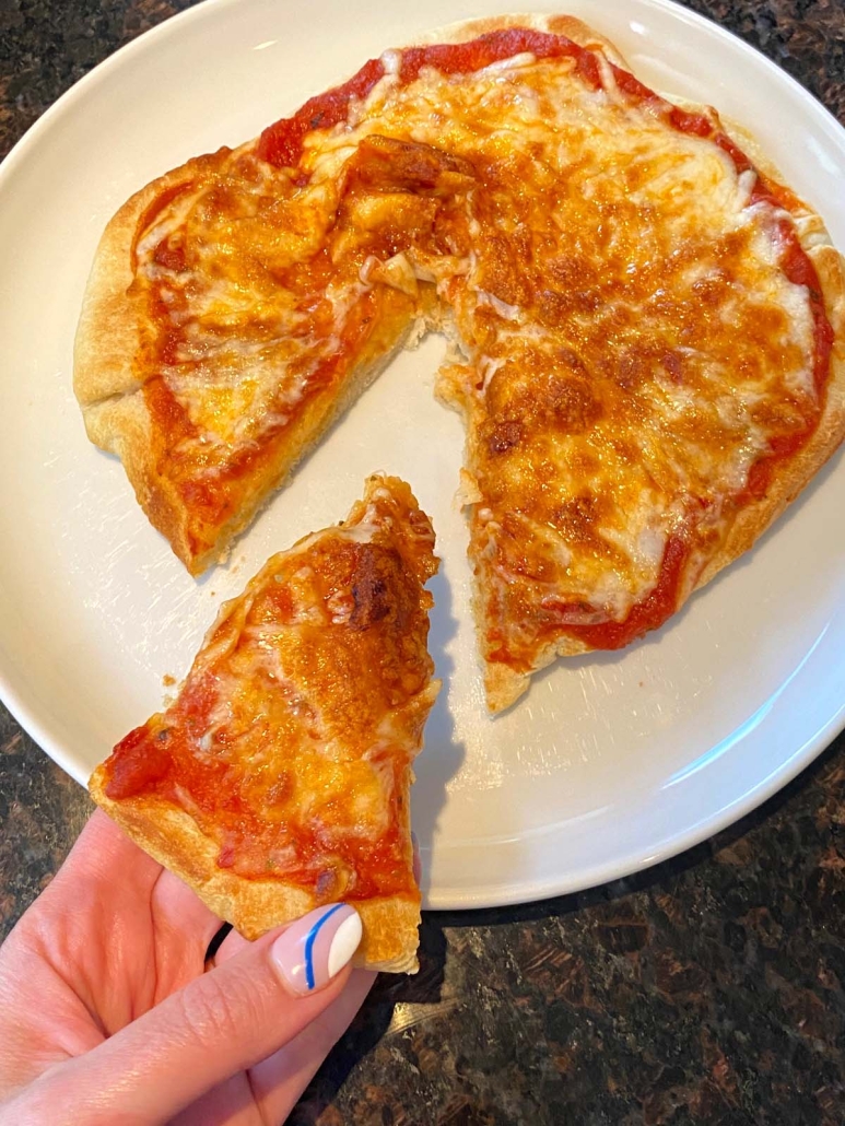 hand holding slice of air fryer pizza