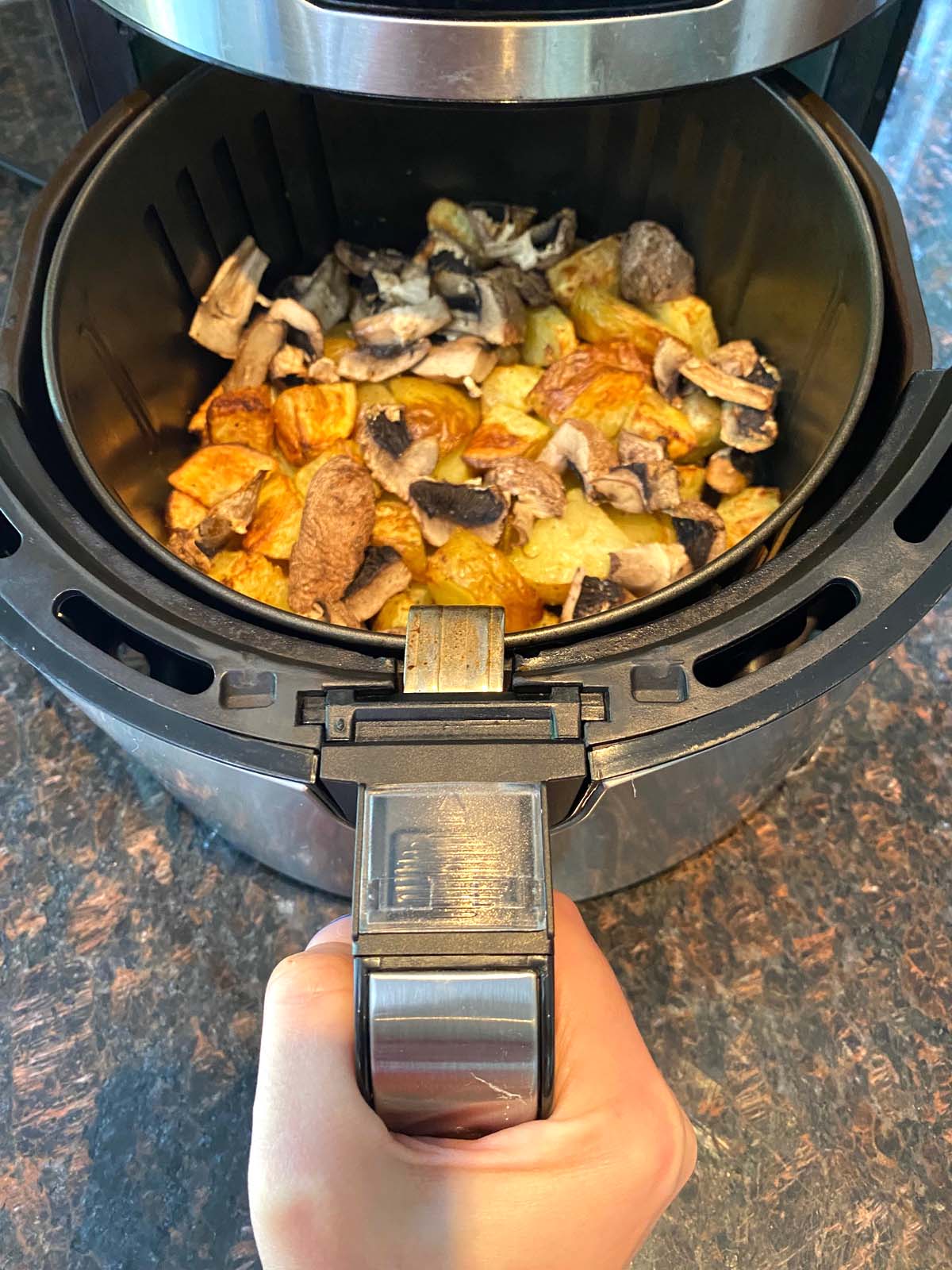 Cooked potatoes and mushrooms in an air fryer.