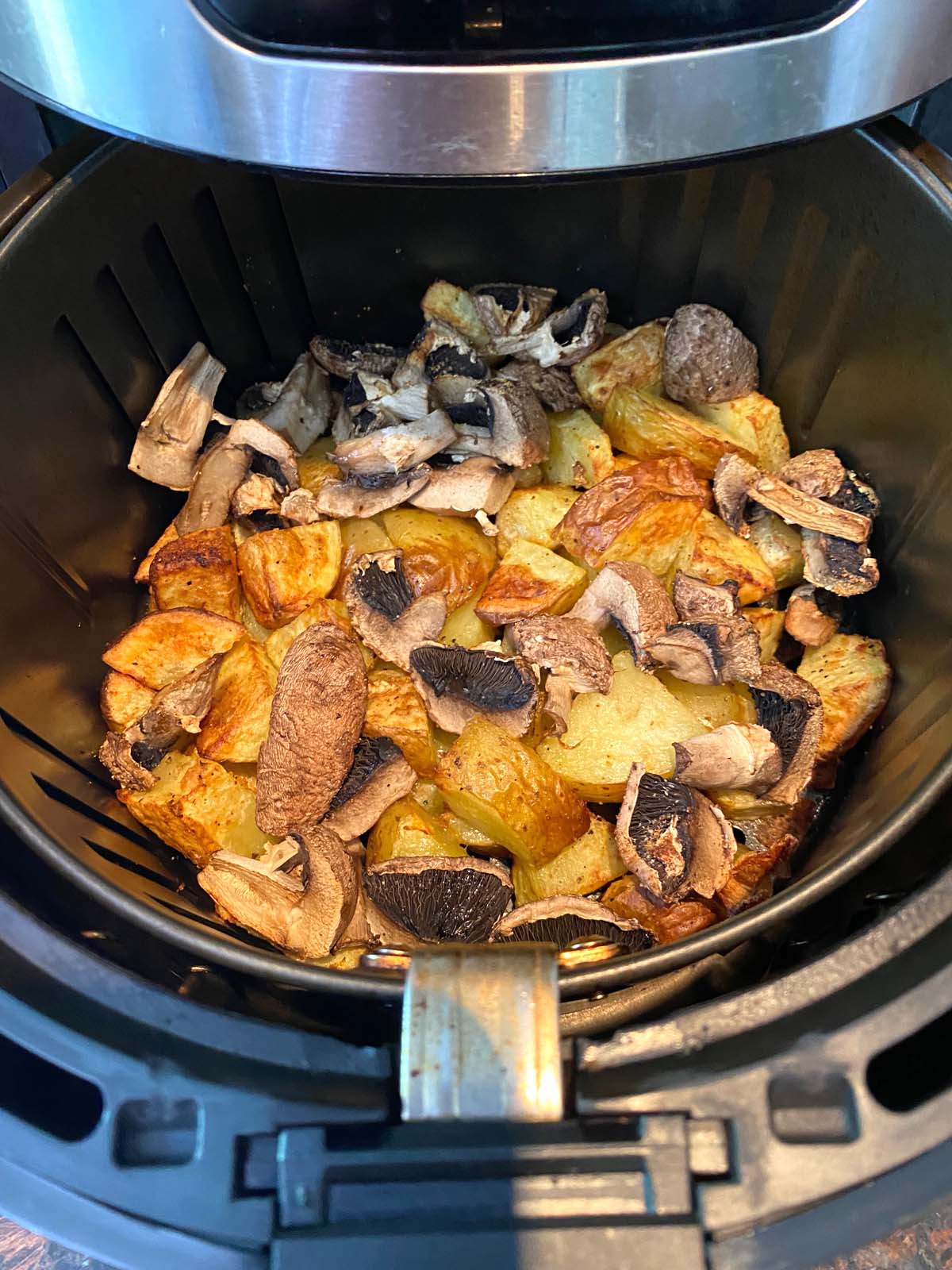 Cooked potatoes and mushrooms in an air fryer.