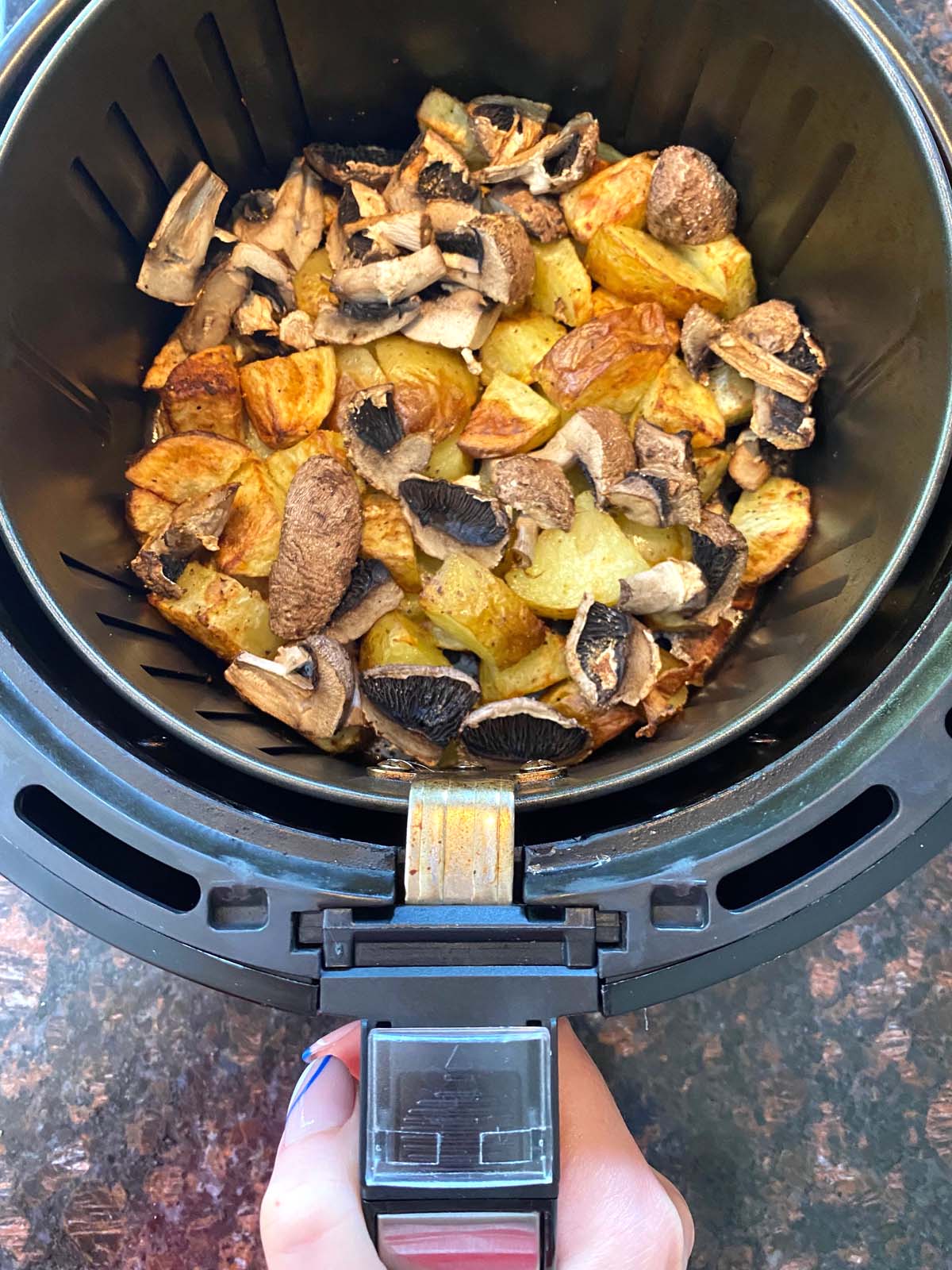 Cooked potatoes and mushrooms in an air fryer.