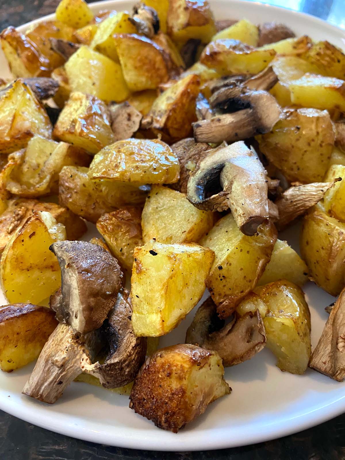 Cooked potatoes and mushrooms on a white plate.