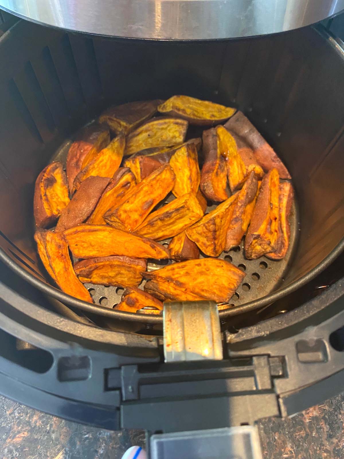 Cooked sweet potato wedges in an air fryer.