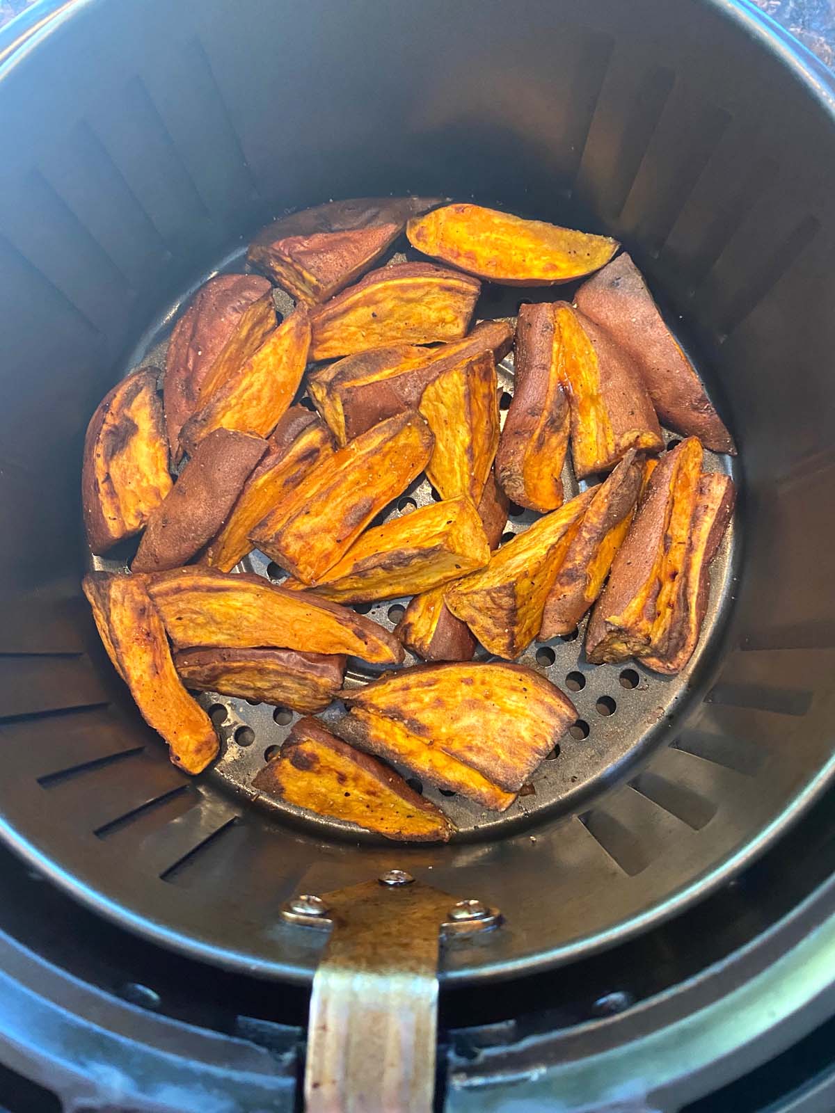 Cooked sweet potato wedges in an air fryer.
