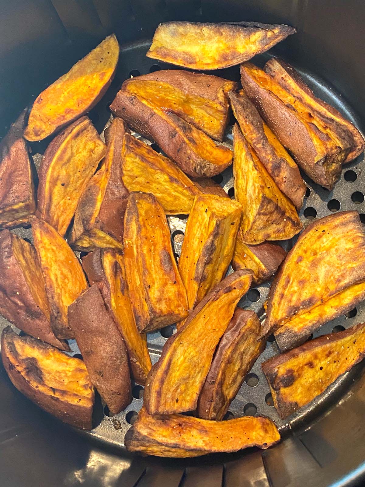 Cooked sweet potato wedges in an air fryer.