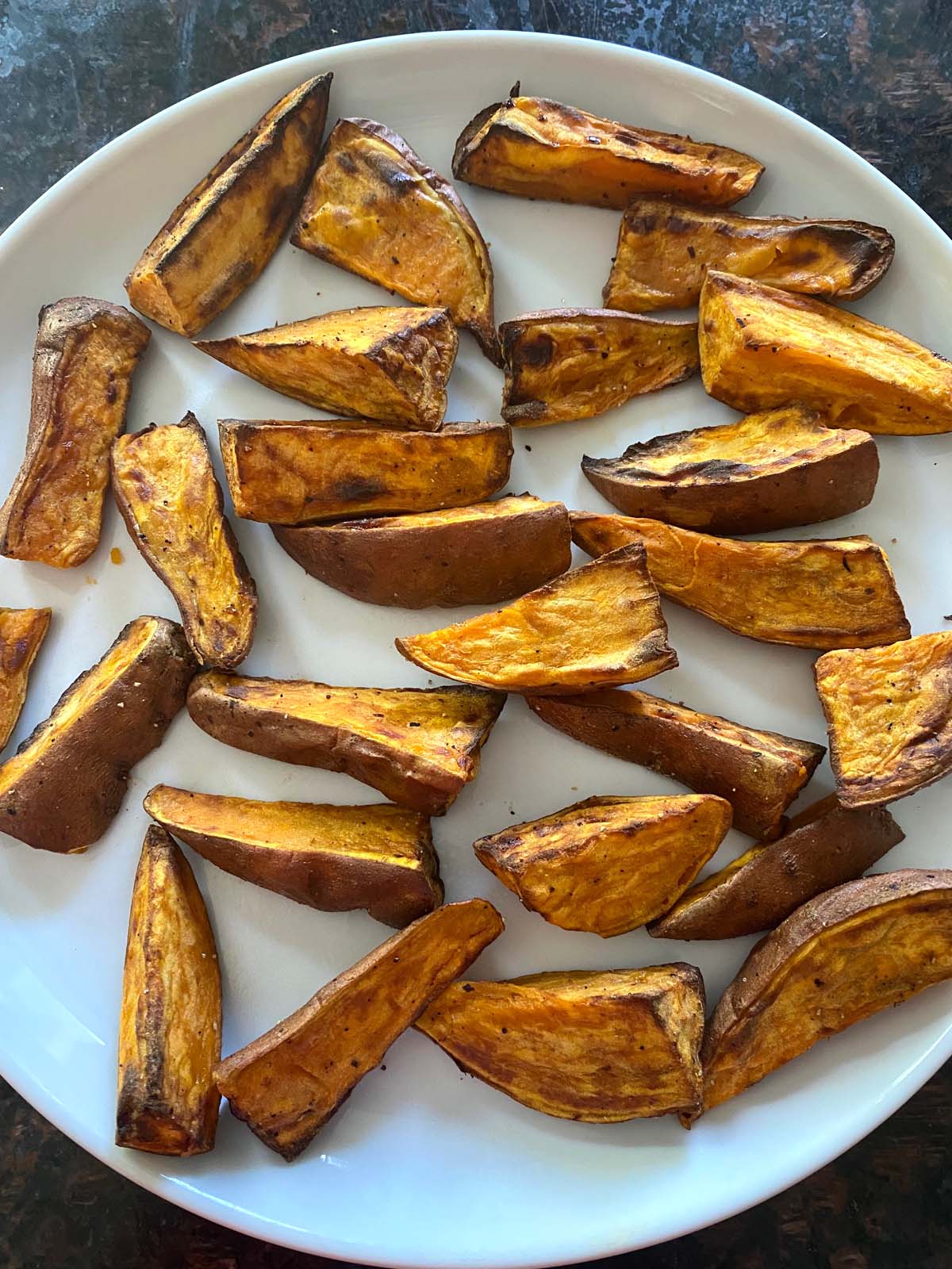 Cooked sweet potato wedges on a white plate.