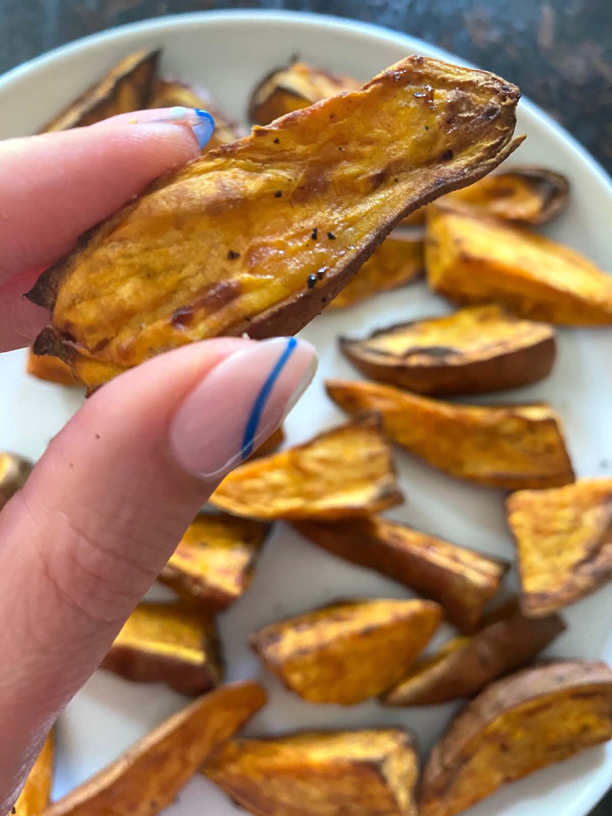Cooked sweet potato wedges on a white plate.