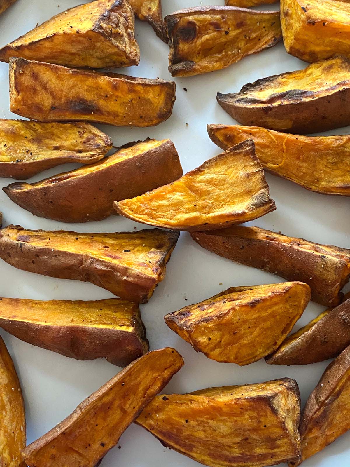 Cooked sweet potato wedges on a white plate.