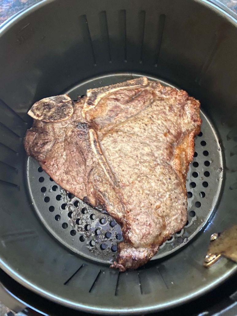 cooked t-bone steak in air fryer basket