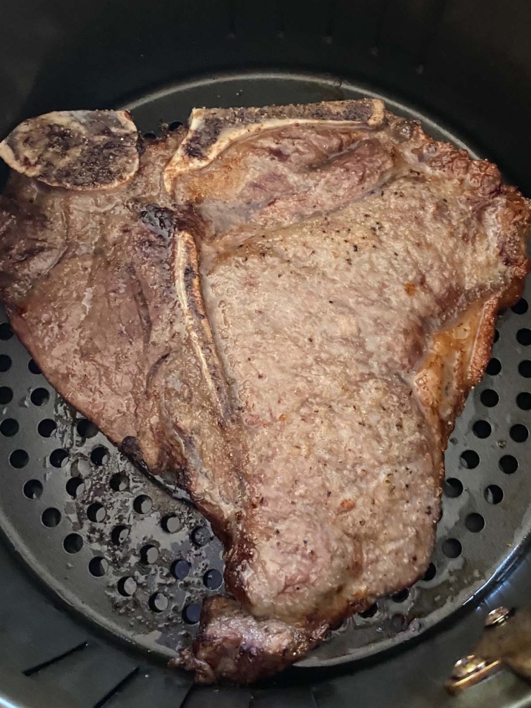 cooked t-bone steak in air fryer basket