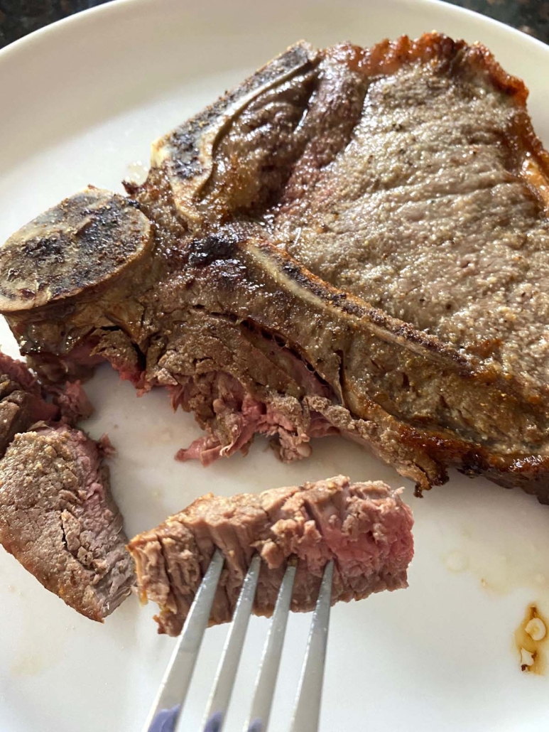 fork holding piece of cooked t-bone steak