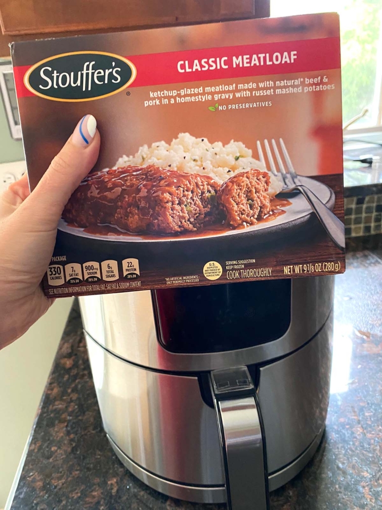 hand holding Stouffer's frozen meatloaf dinner in front of air fryer
