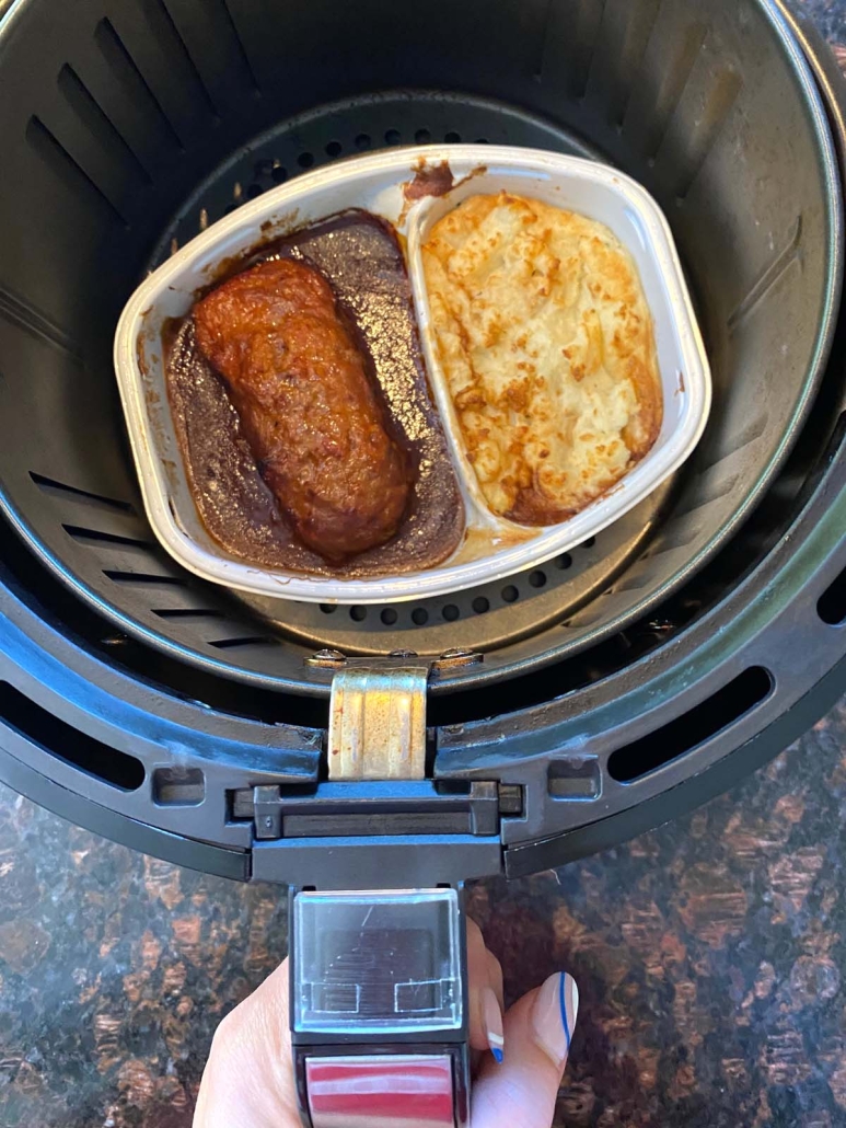 air fryer basket with frozen meatloaf meal inside