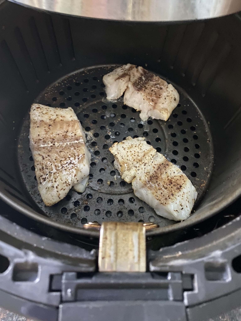 air fryer opened to show cooked cod