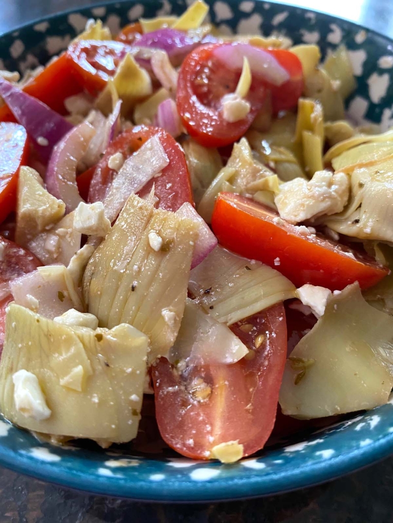 bowl of artichoke salad with tomatoes and red onion