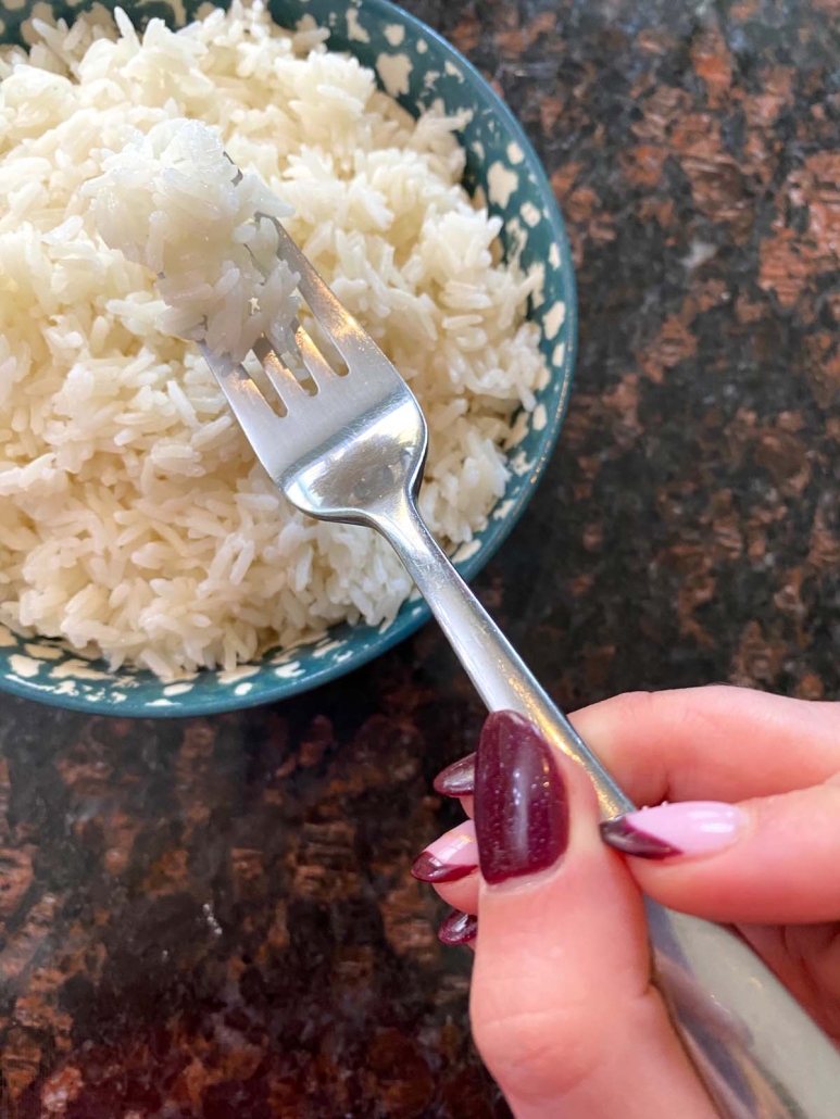 hand holding fork with cooked jasmine rice