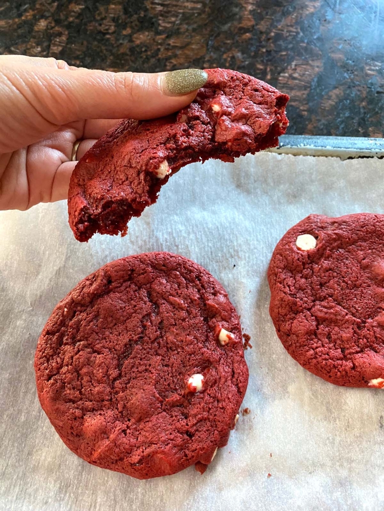 hand holding half of a red velvet cookie