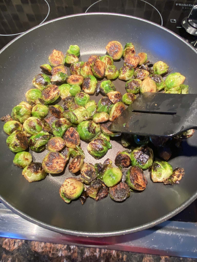 spatula stirring Brussels sprouts in skillet