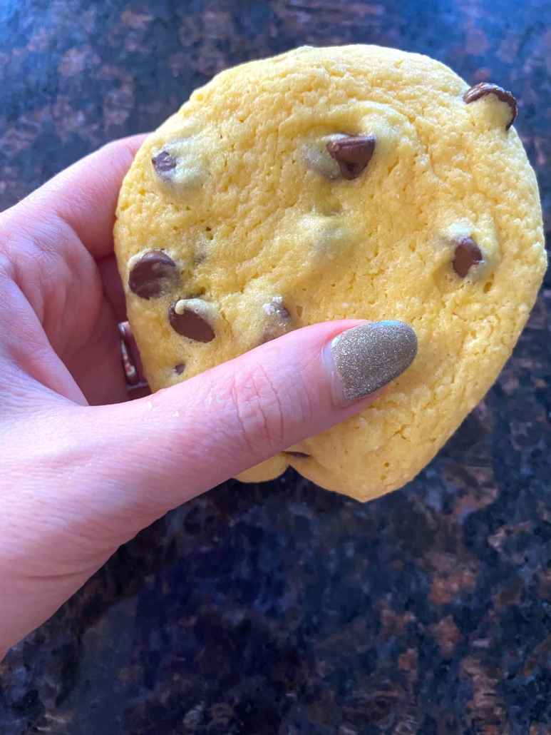 hand holding yellow cake mix cookie with chocolate chips