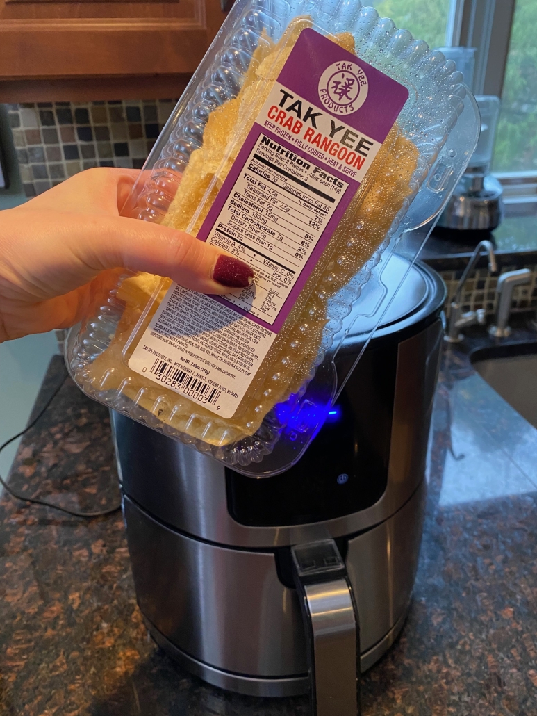 package of frozen crab rangoon in front of air fryer