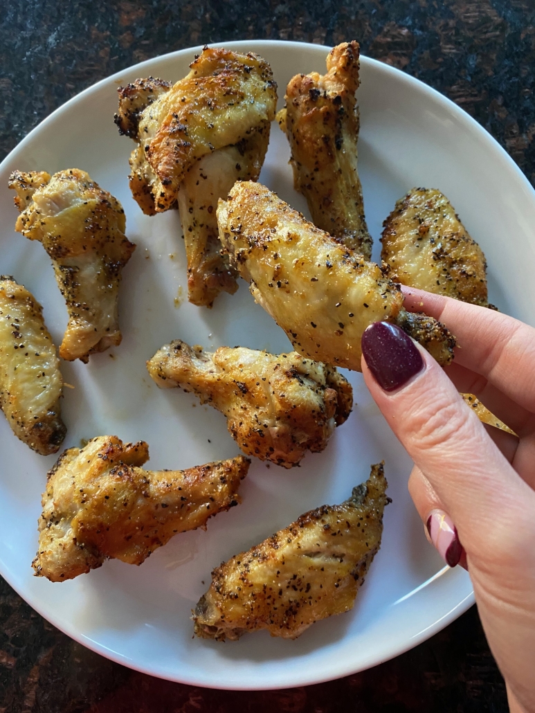 hand holding cooked lemon pepper chicken wing