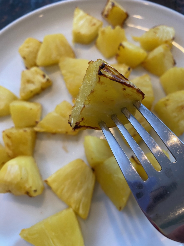 fork holding piece of air fryer pineapple