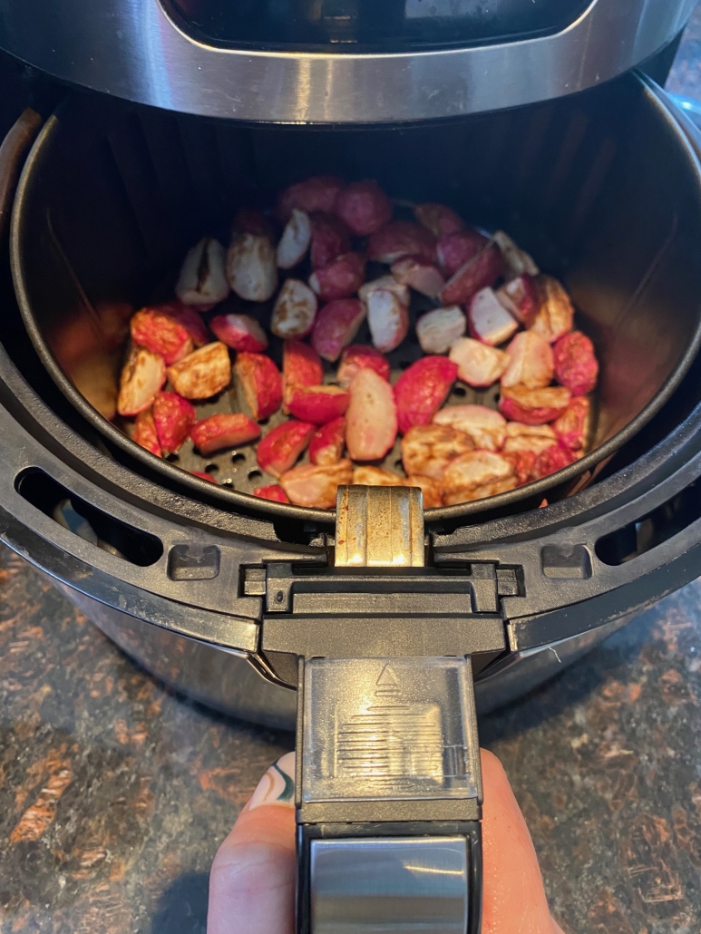 air fryer opened to show cooked, seasoned radishes