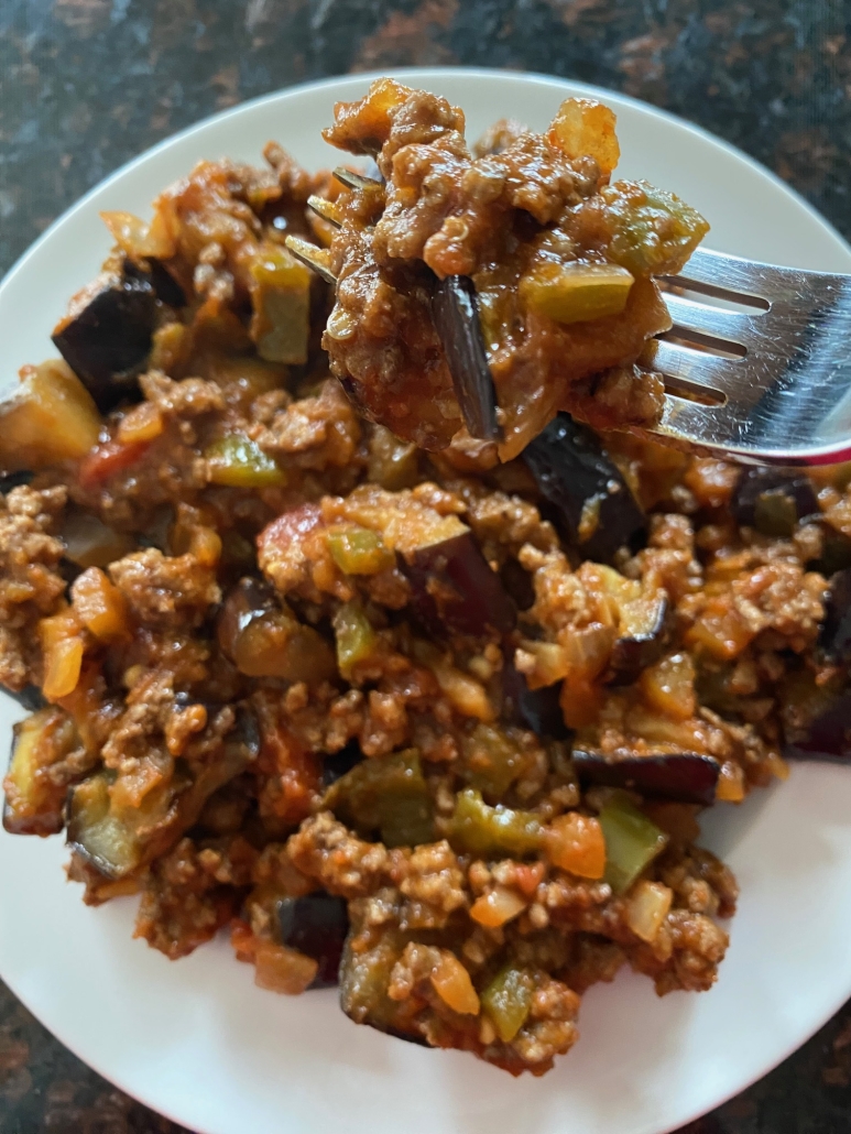 fork digging into plate of ground beef and eggplant