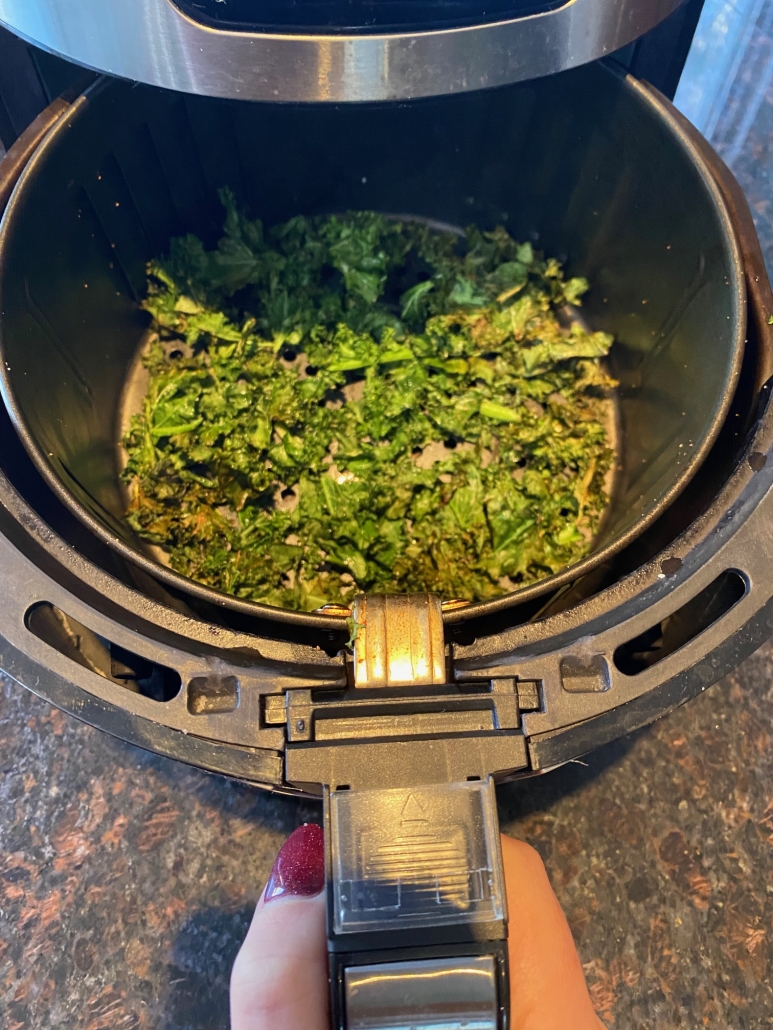 air fryer opened to show seasoned kale chips