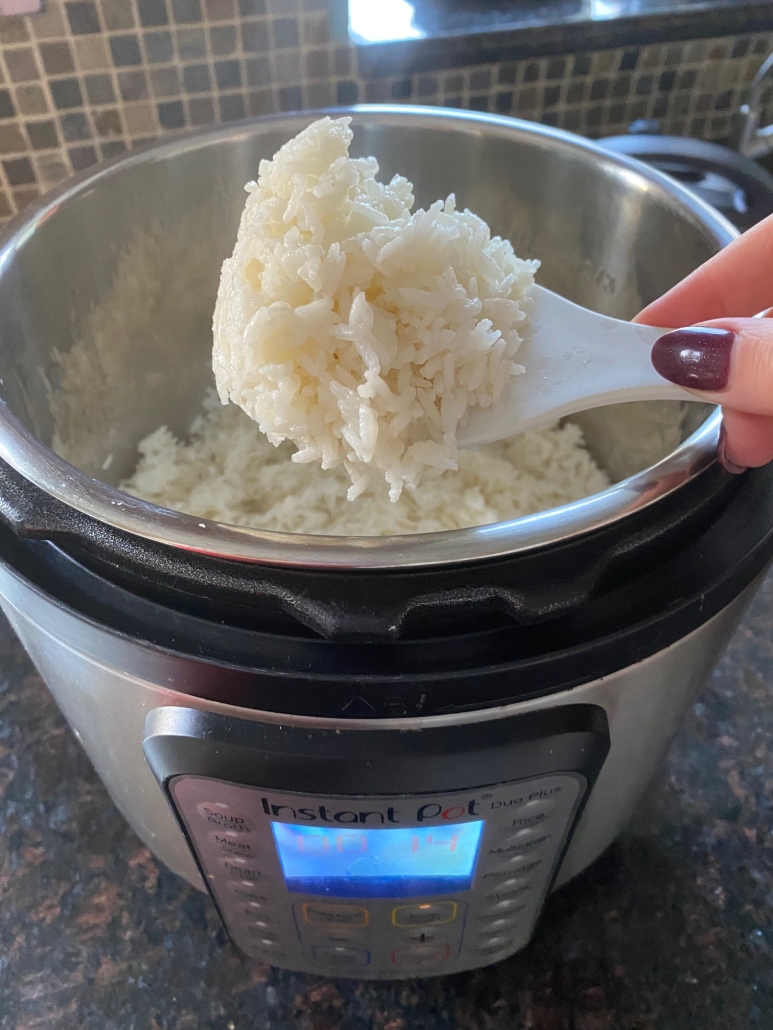 hand scooping out coconut rice from instant pot