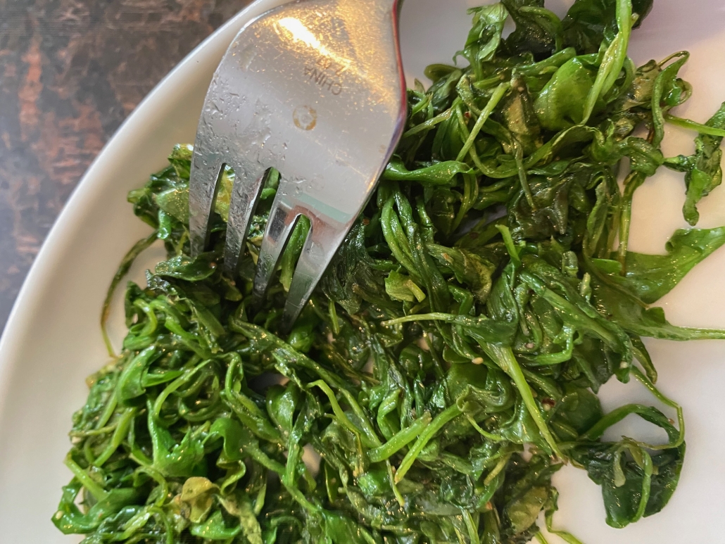 fork in a plate of sautéed arugula