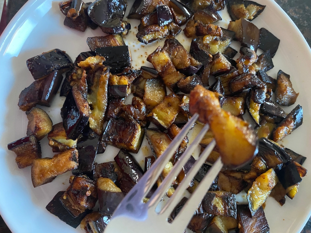 fork holding a piece of sautéed eggplant