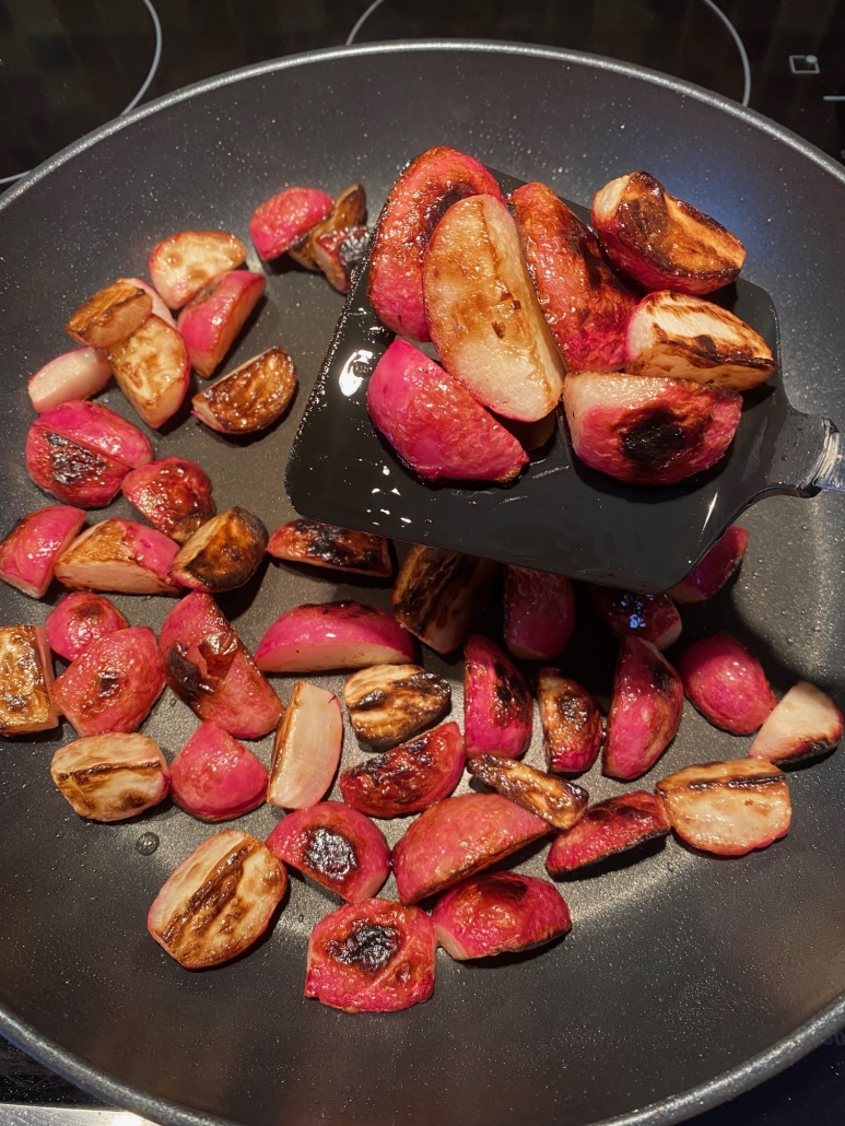 spatula tossing cooked radishes in skillet