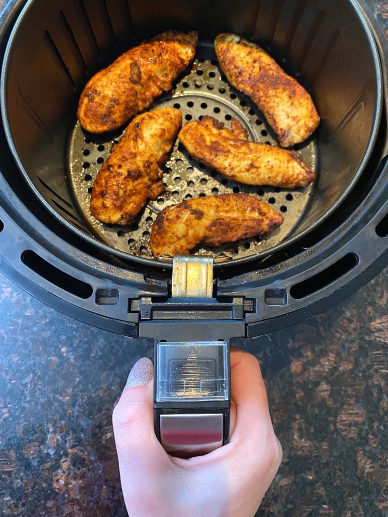 hand holding air fryer with Chicken Tenders No Breading