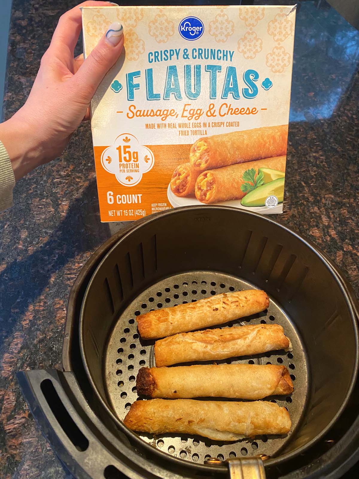 Cooked flautas in an air fryer and a box of frozen flautas.