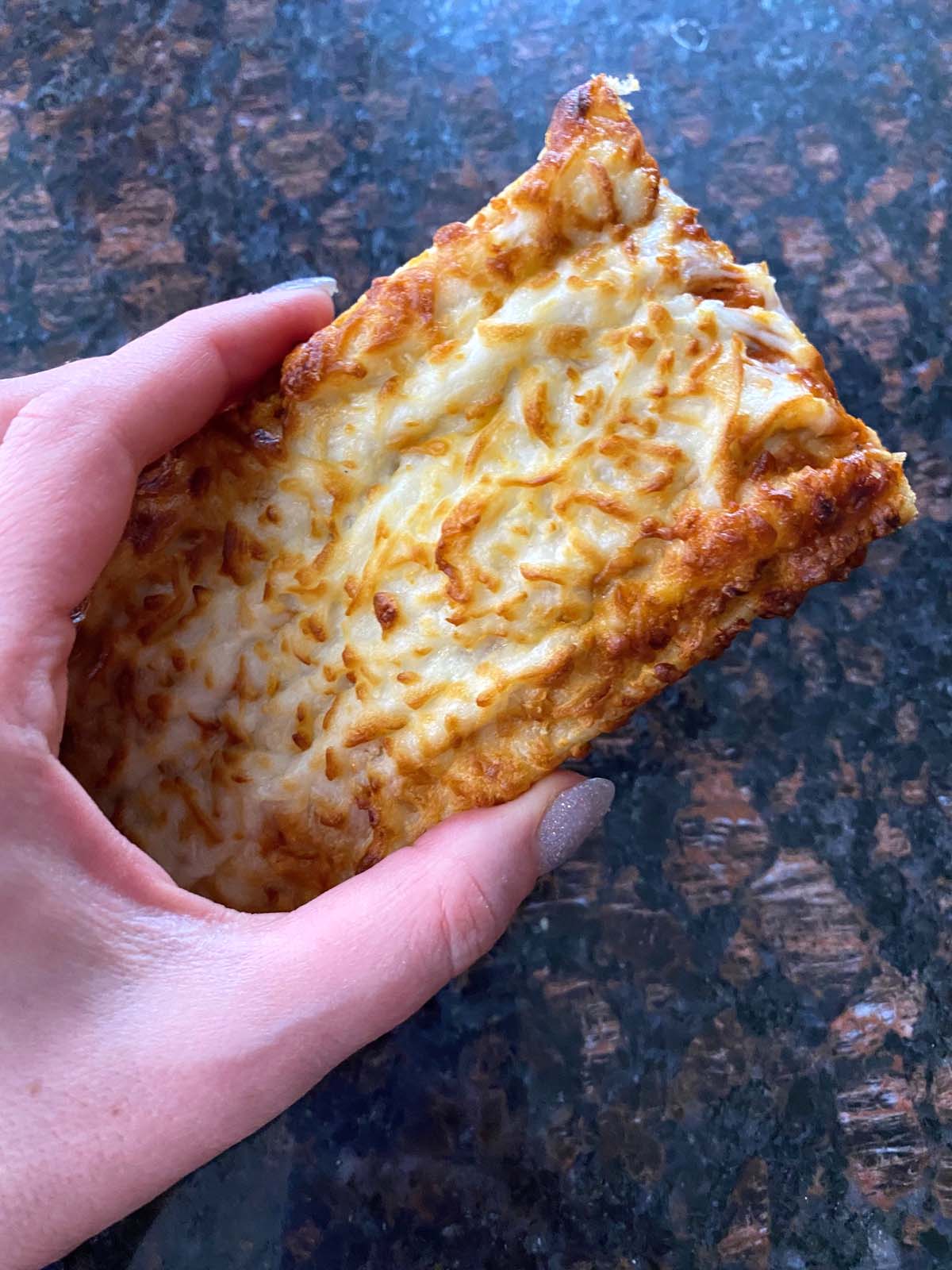 Some holding cooked French bread pizza.