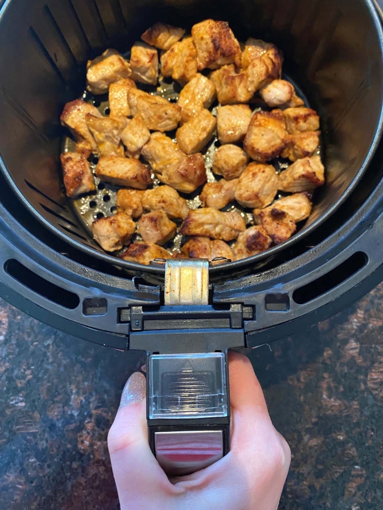 hand holding air fryer with pork bites inside