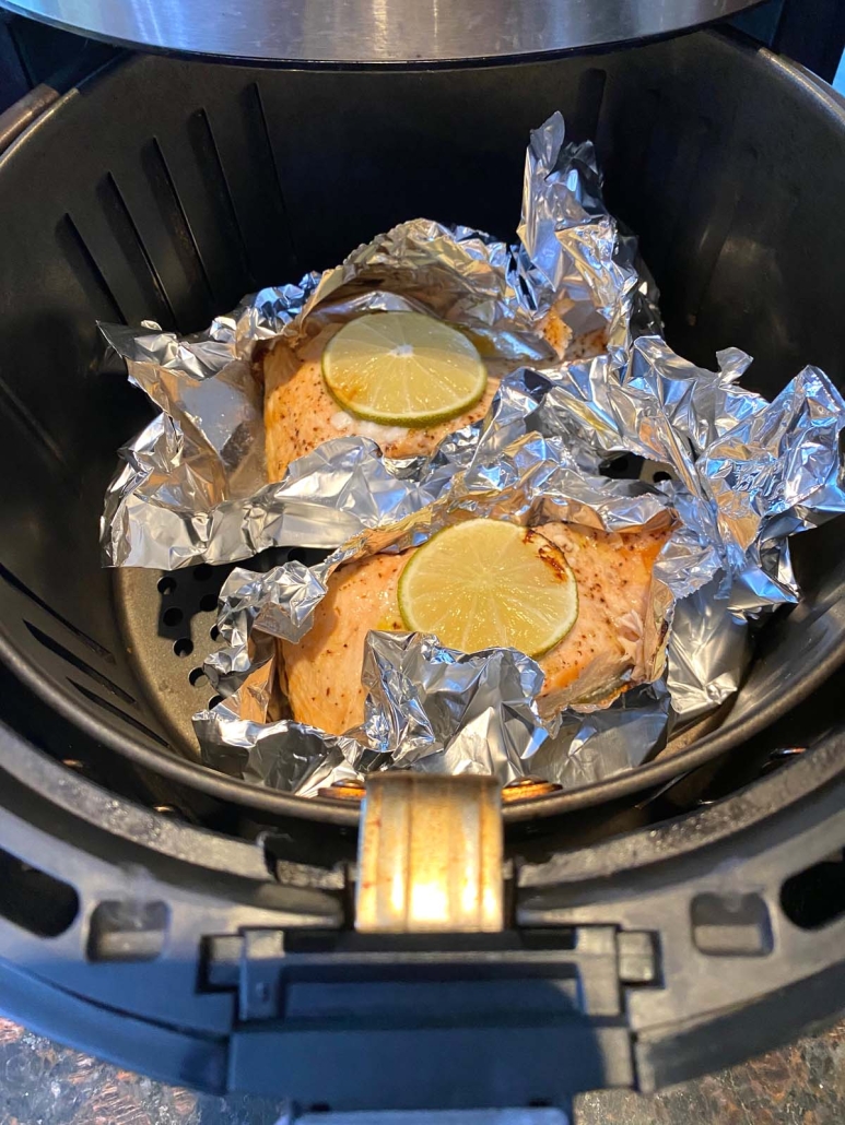 air fryer opened to show foil packets of salmon