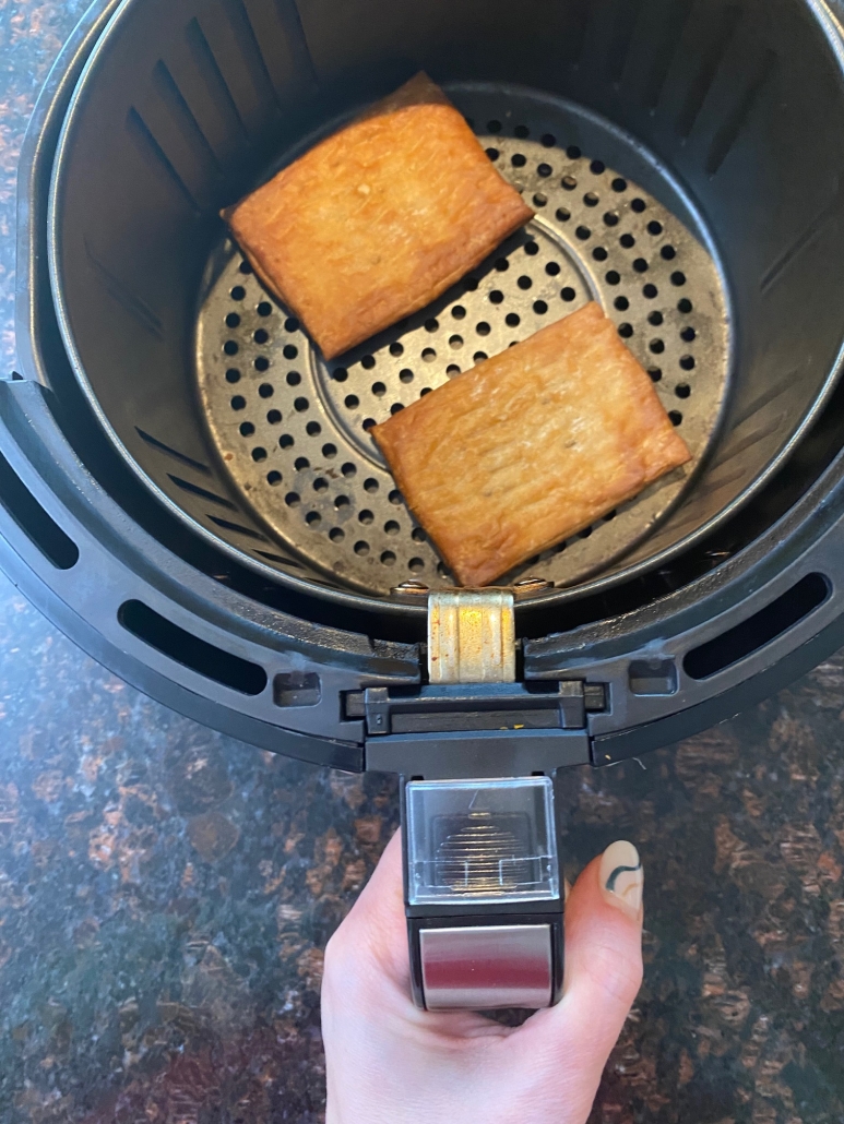 hand holding air fryer with Toaster Scrambles inside