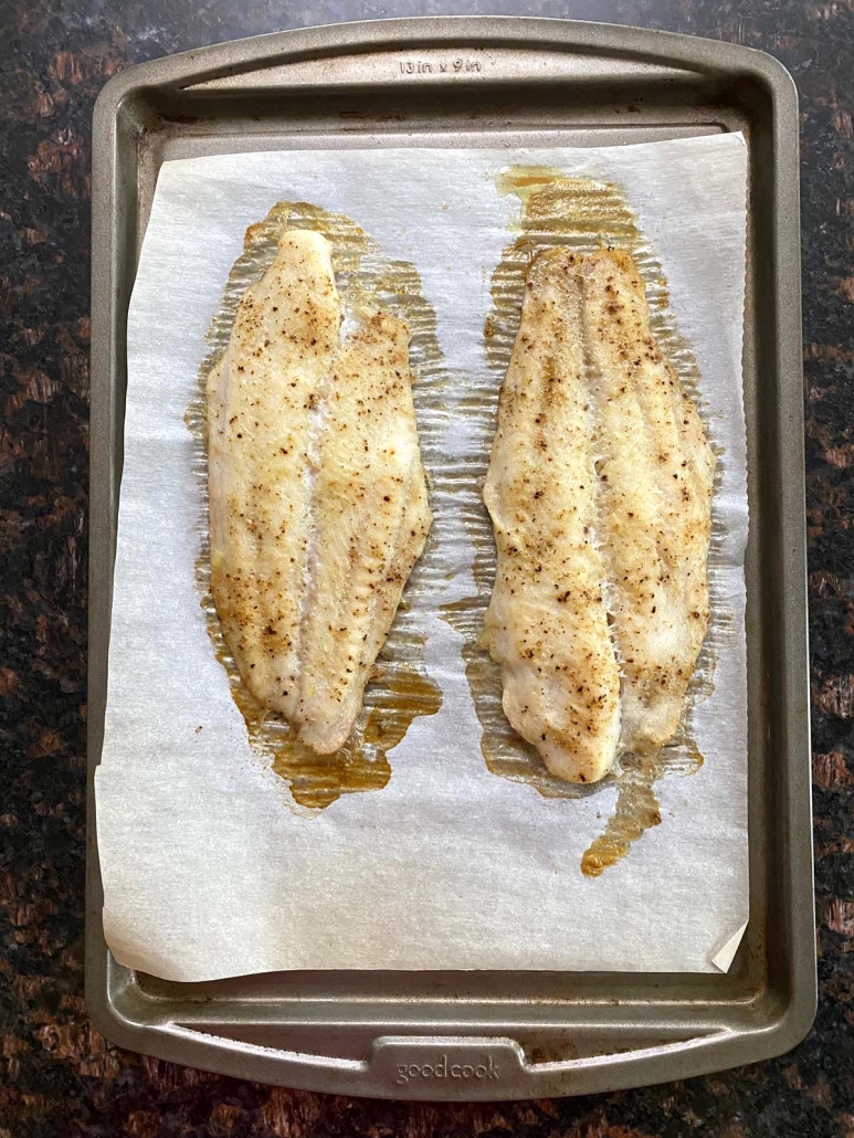 seasoned white fish on a baking sheet