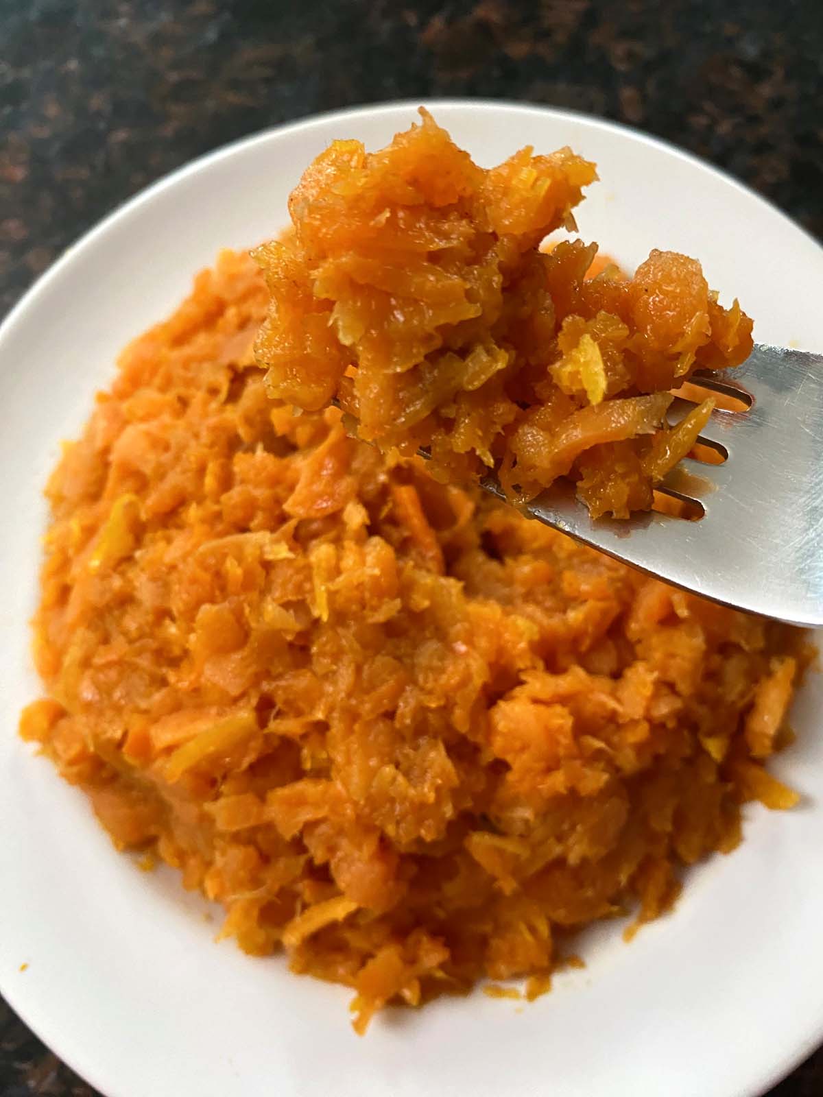 Mashed carrots in a white bowl.