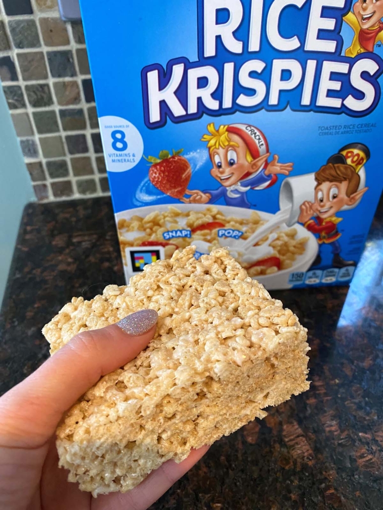 hand holding Microwave Rice Krispie Treat in front of box of cereal