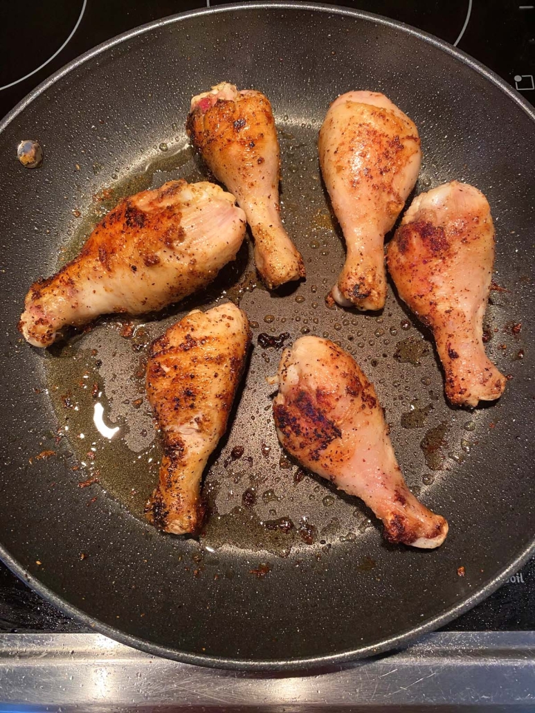 skillet with cooking chicken drumsticks