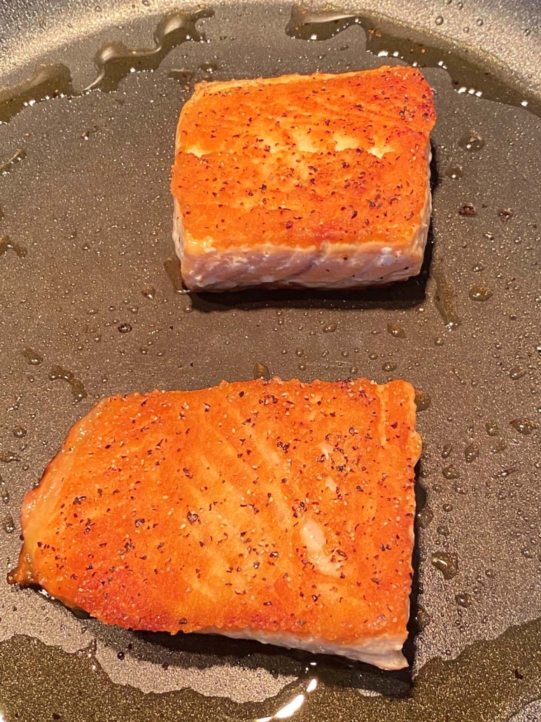 golden brown salmon in a frying pan