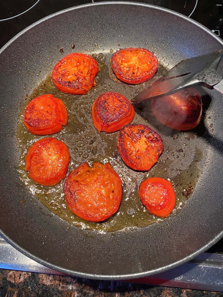 flipping slices of tomato in a hot skillet