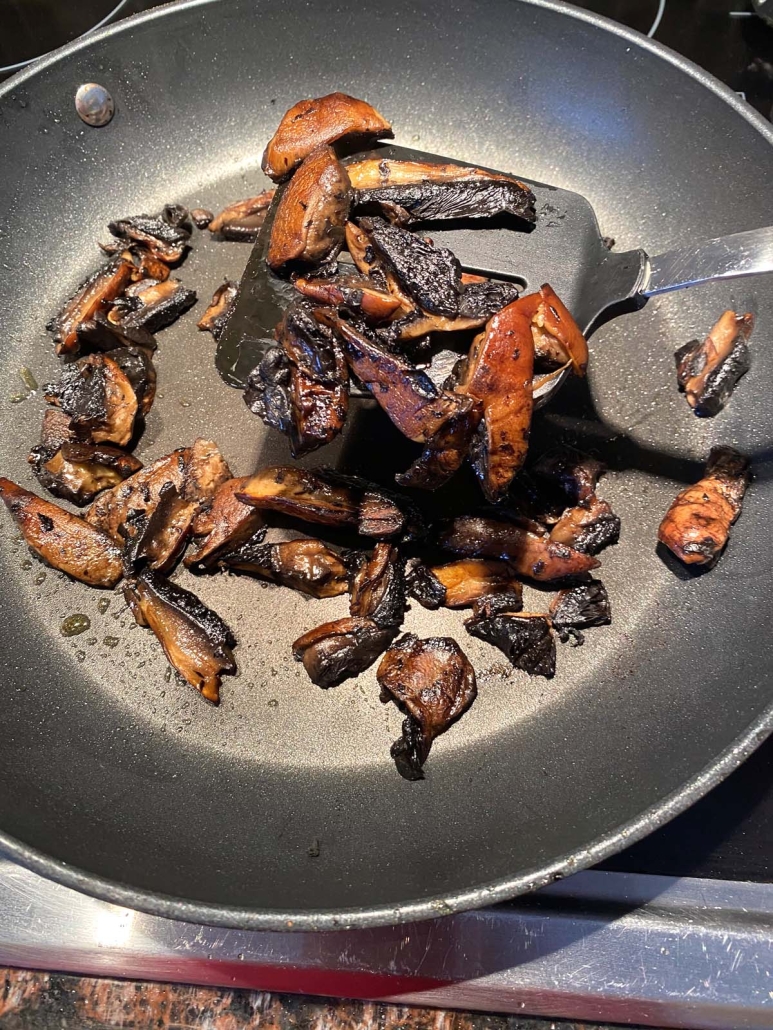 sliced portobello mushrooms sautéing in a skillet